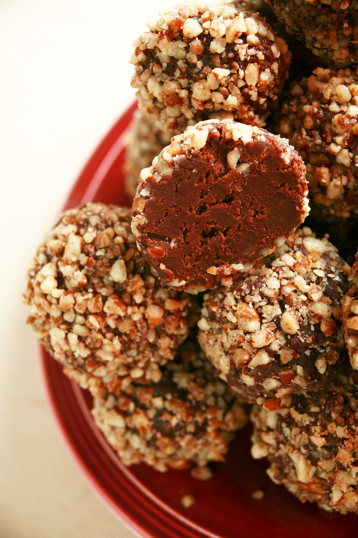 A red plate piled high with sugar-free bananas foster truffles. They are coated in crushed pecans.