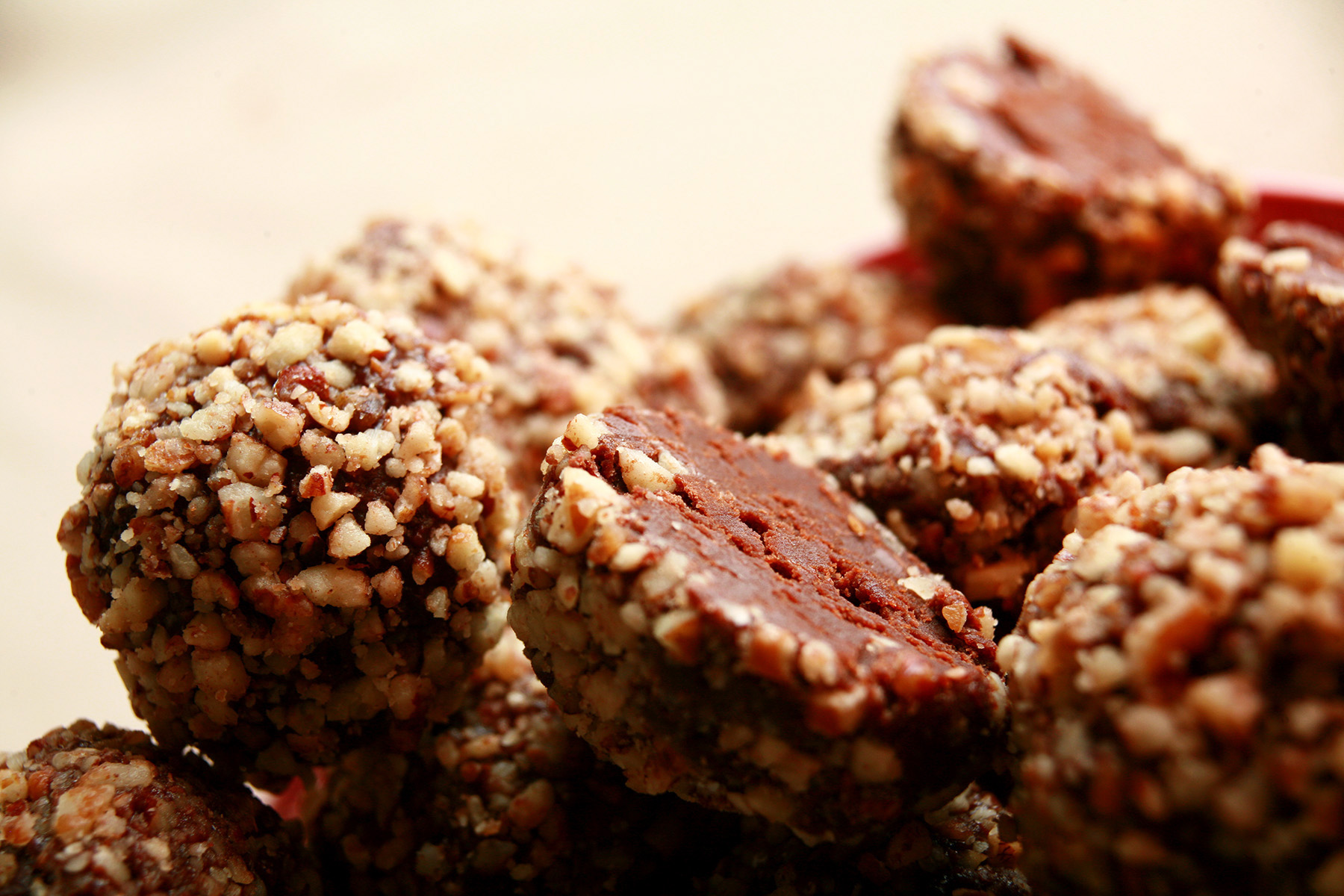 A red plate piled high with low carb bananas foster truffles. They are coated in crushed pecans.