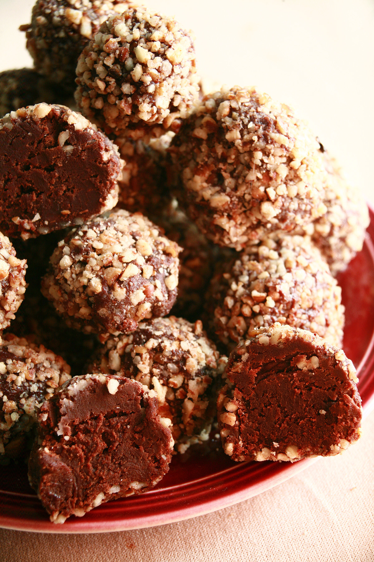 A red plate piled high with sugar-free bananas foster truffles. They are coated in crushed pecans.