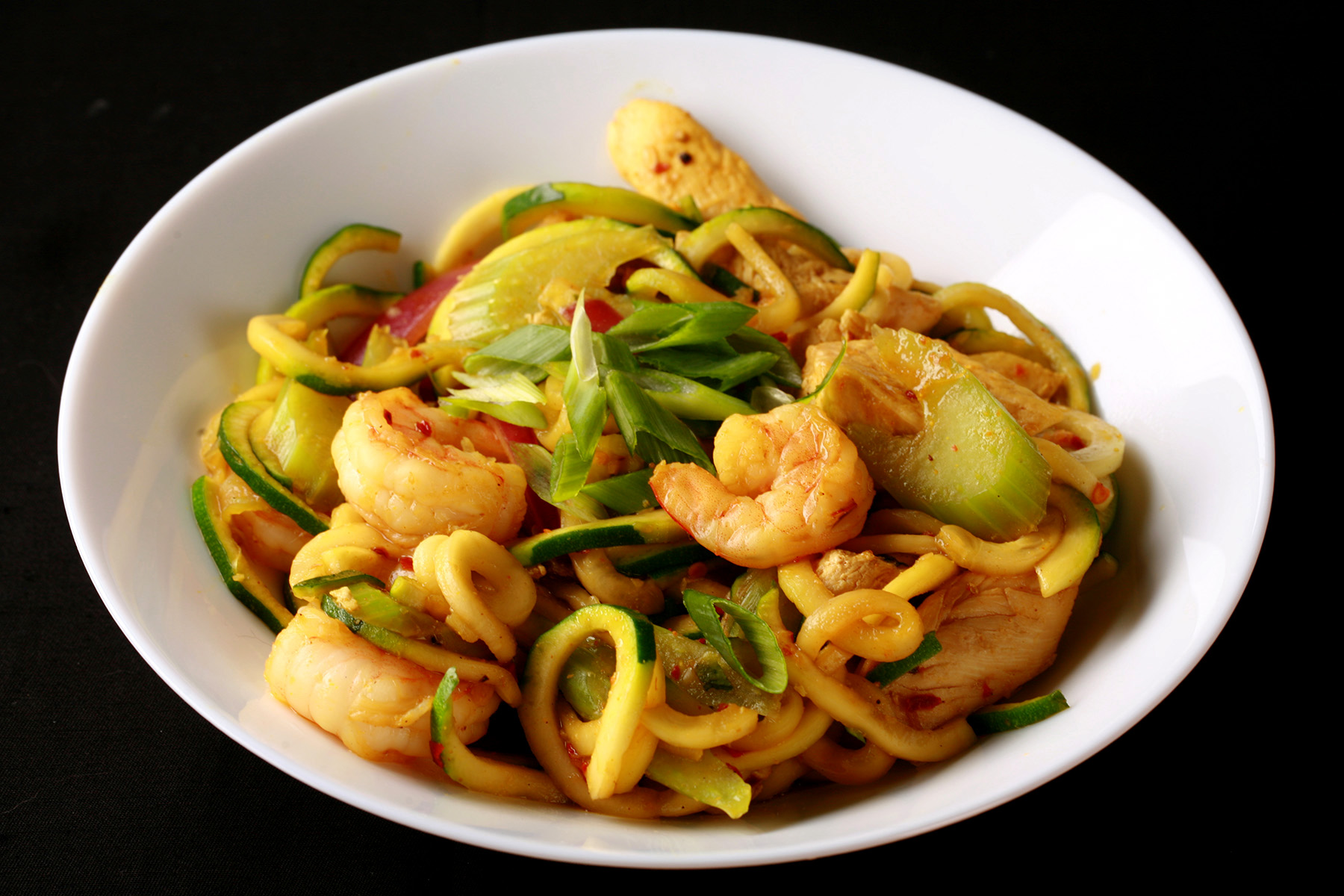 A white bowl with singapore mai fan style zoodles.