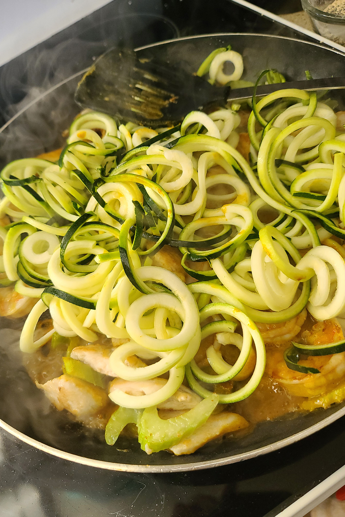 Zoodles being cooked in the sauce.