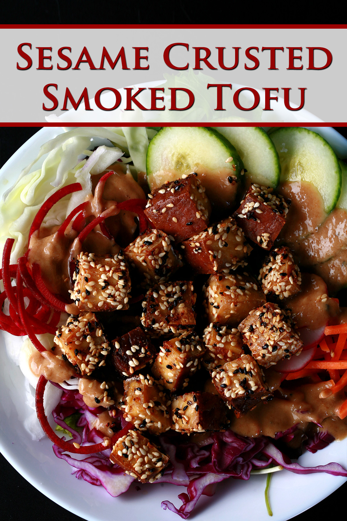 Cubes of sesame crusted smoked tofu on top of a colourful salad. Cucumbers, beets, carrots, and purple cabbage are visible.