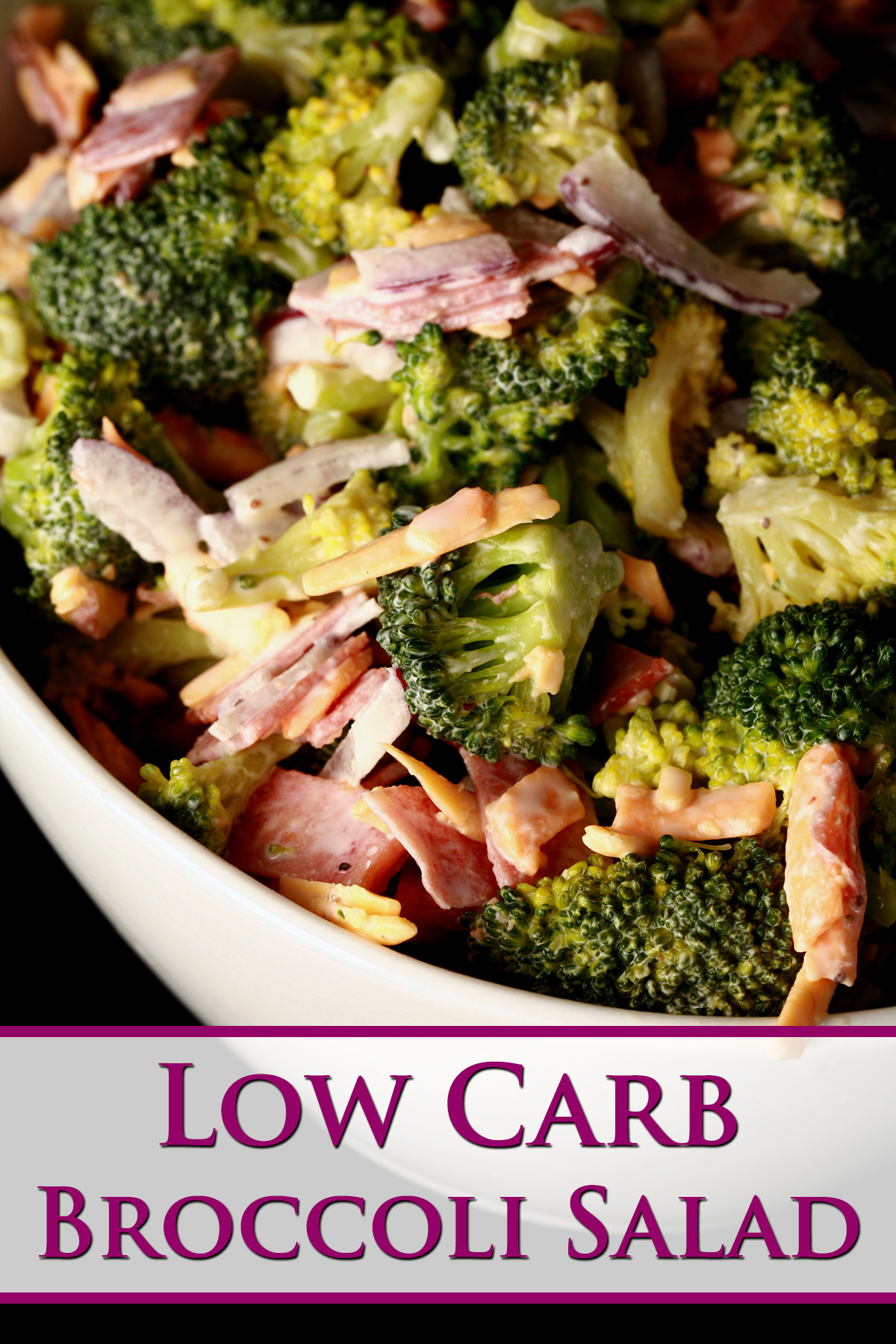 A bowl of keto broccoli salad. Broccoli, chicken bacon, cheese, and red onion slices in a white dressing.