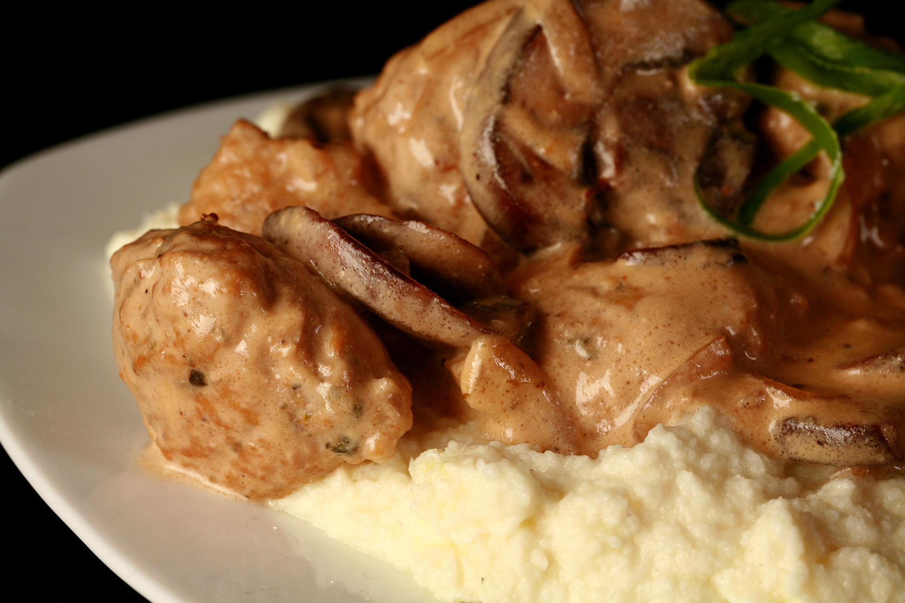 Low carb chicken meatballs in a mushroom cream sauce, over a pile of mashed cauliflower.