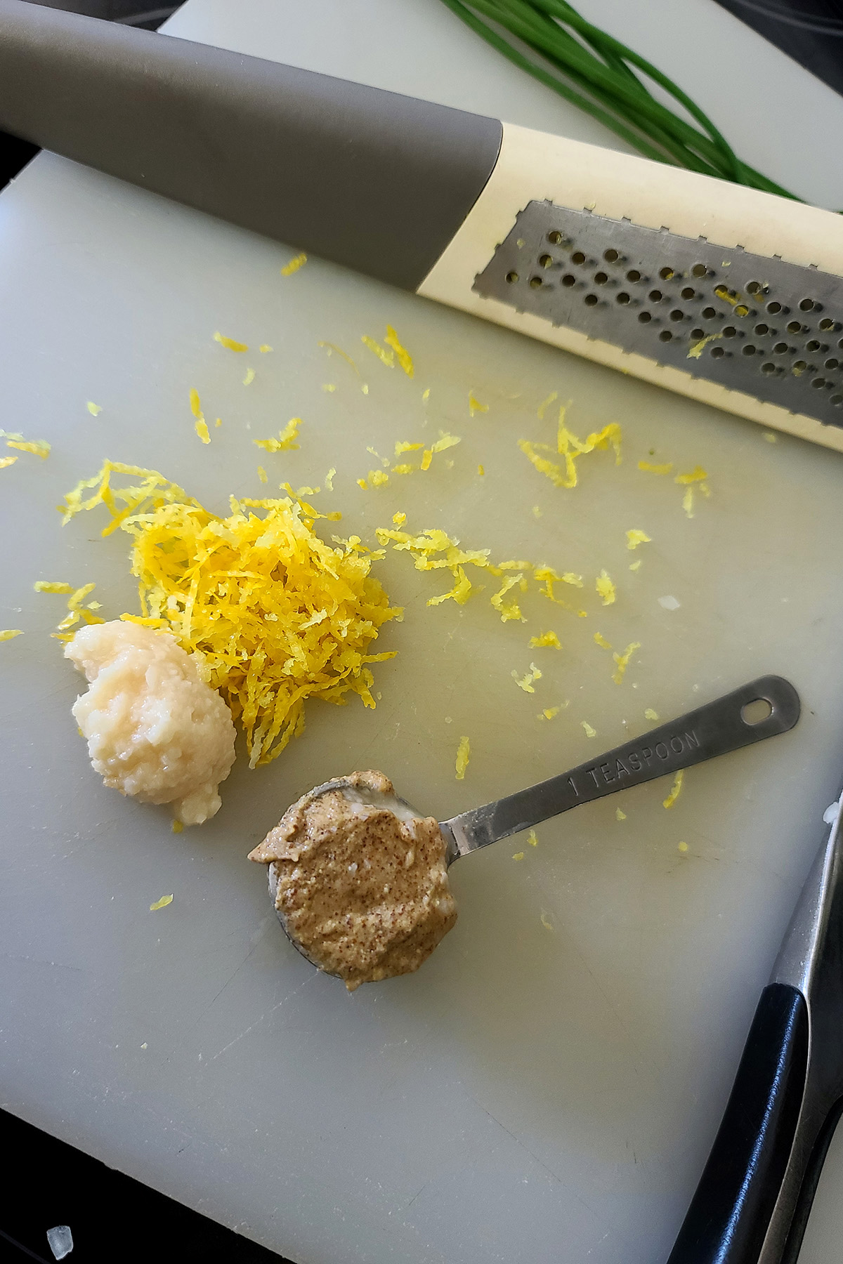 Garlic, mustard, and lemon zest on a cutting board.