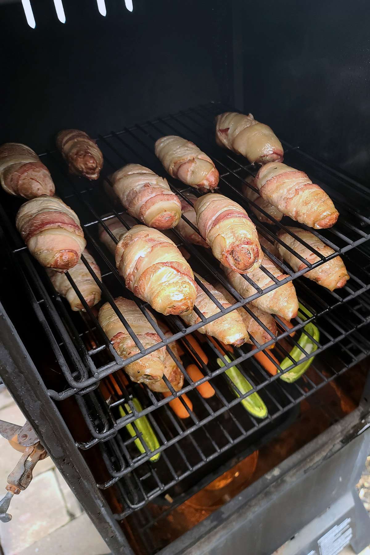 Bacon wrapped armadillo eggs being cooked in a smoker.