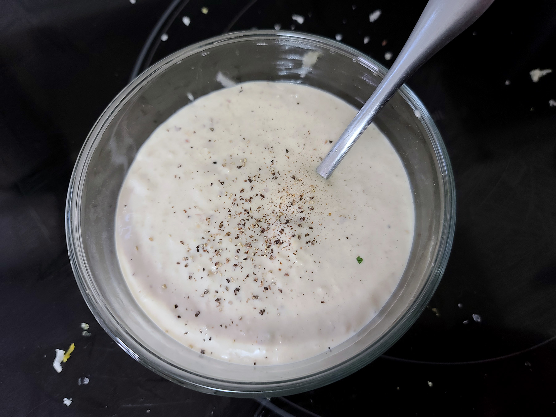 A bowl of low carb Caesar dressing with pepper sprinkled on top.