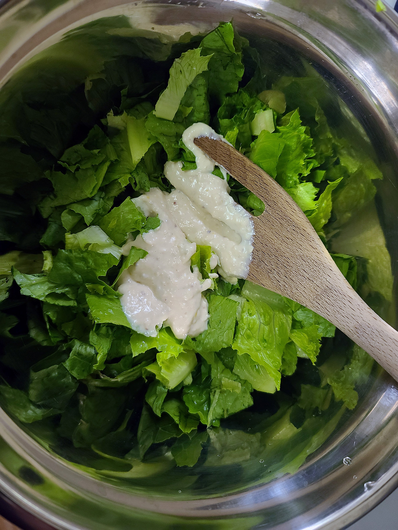 A bowl of romaine lettuce, with a glob of Caesar dressing on top.