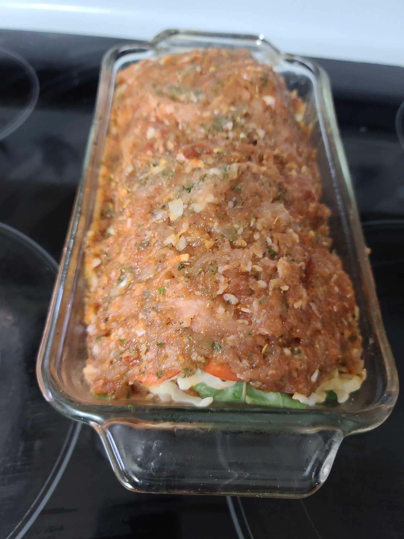 The rolled chicken stromboli meatloaf in a glass loaf pan.