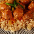 A plate of creamy low carb buffalo chicken meatballs, served on a bed of celery rice.