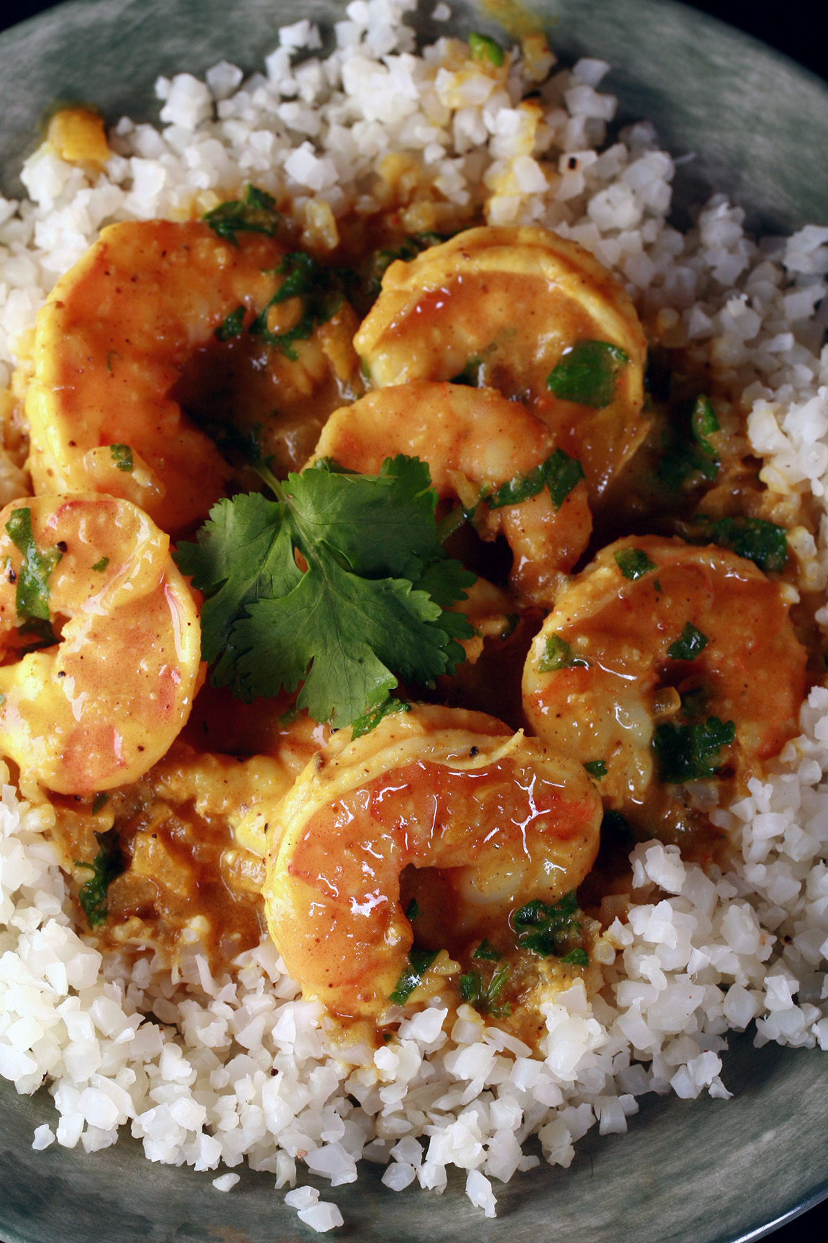 Low carb shrimp curry, served over a bowl of cauliflower rice and garnished with cilantro.