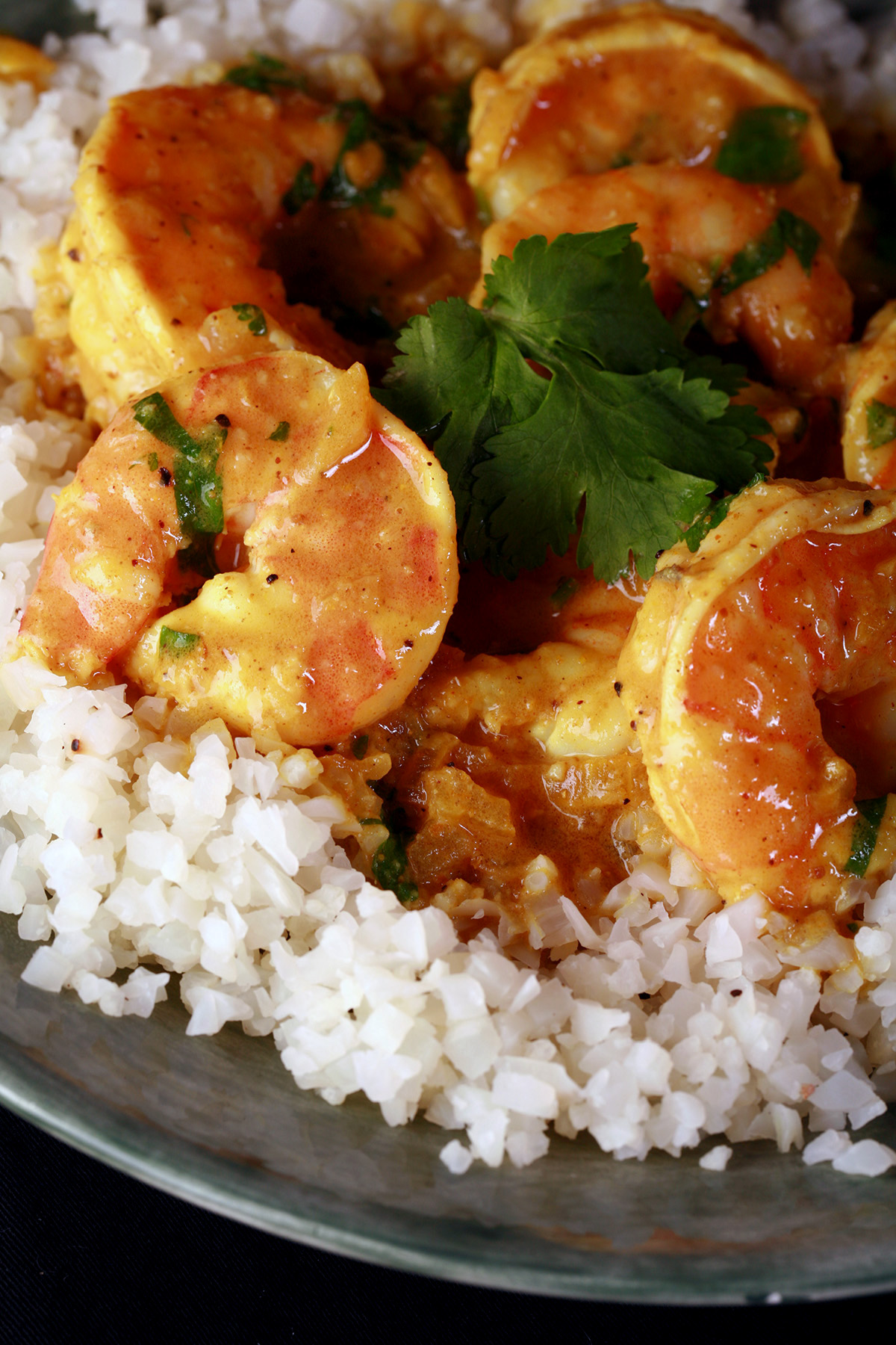 Keto shrimp curry, served over a bowl of cauliflower rice and garnished with cilantro.