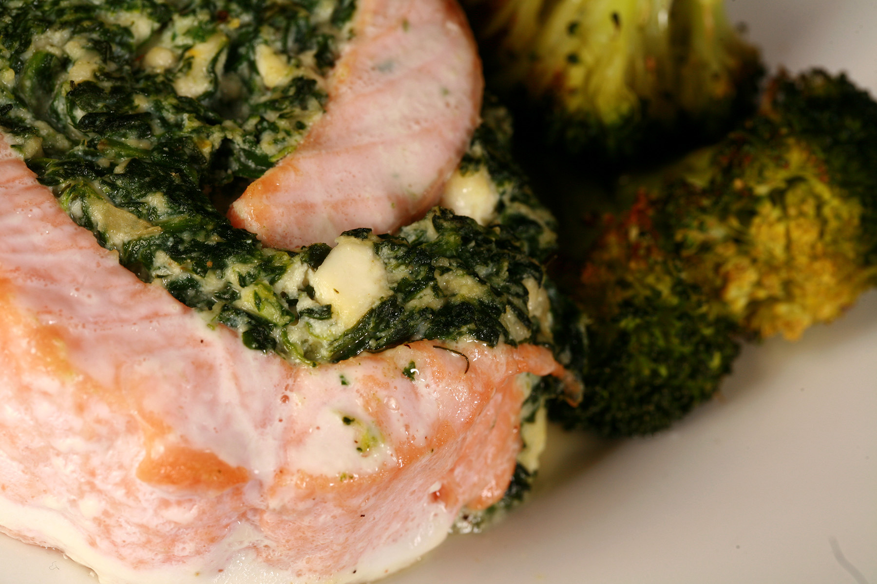A serving of spinach and feta stuffed salmon, along with some roasted broccoli on a plate.