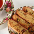 4 pieces of low carb biscotti on a fine china plate, next to a cup of tea.