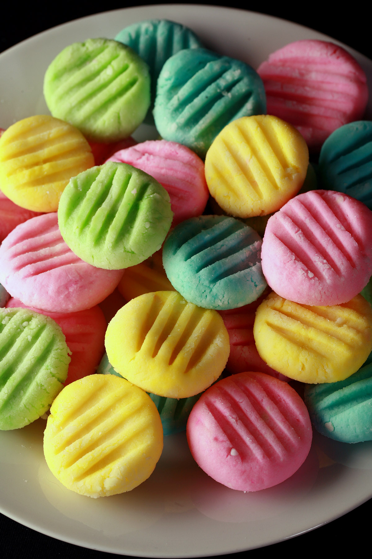 A plate piled high with sugar free cream cheese mints. They are pink, yellow, green, and blue.