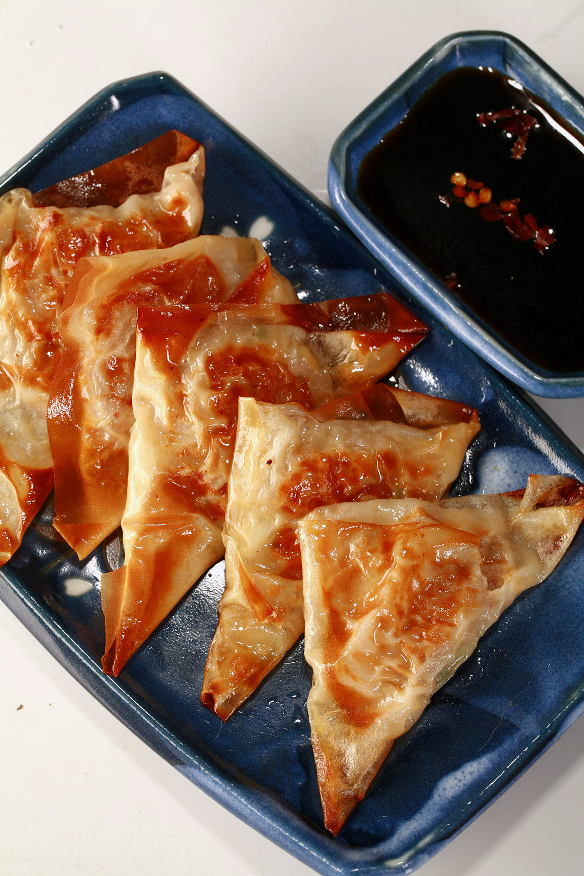 A blue rectangular dish with 5 keto potstickers on it.