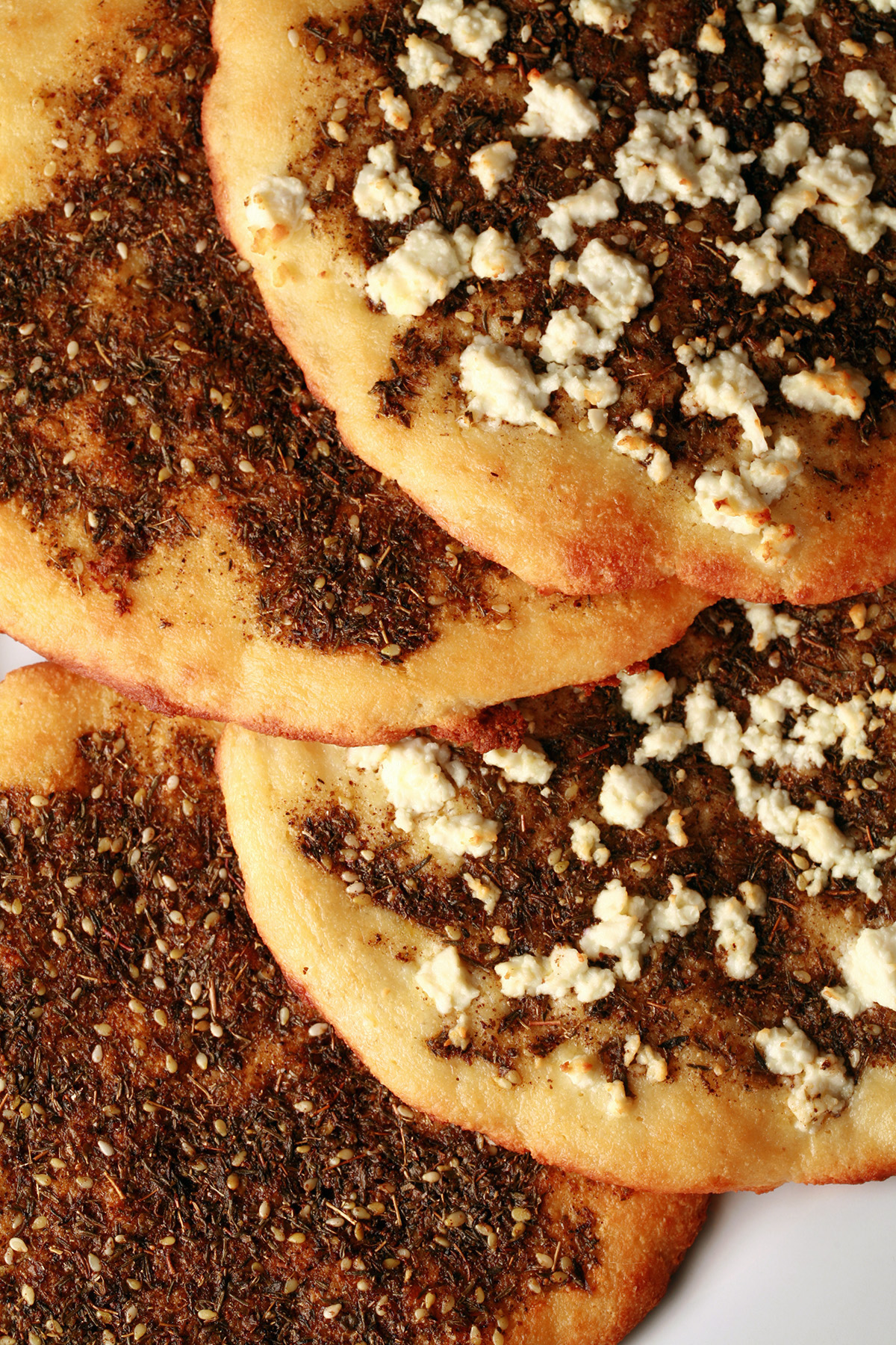 A white platter with 4 keto manakish on it. 2 are topped with Zaatar, 2 with Za'atar and cheese.