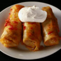 Low carb cabbage rolls on a plate, garnished with a large dollop of sour cream.