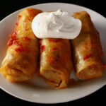 Low carb cabbage rolls on a plate, garnished with a large dollop of sour cream.