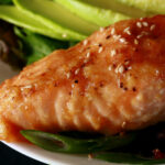 A glazed portion of keto sesame ginger salmon, in a bowl of veggies.