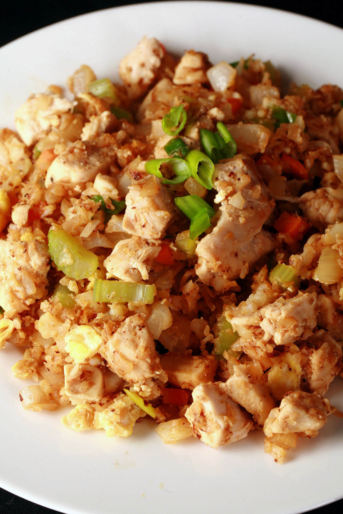 A heaping serving of keto cauliflower chicken fried rice, in a white bowl.