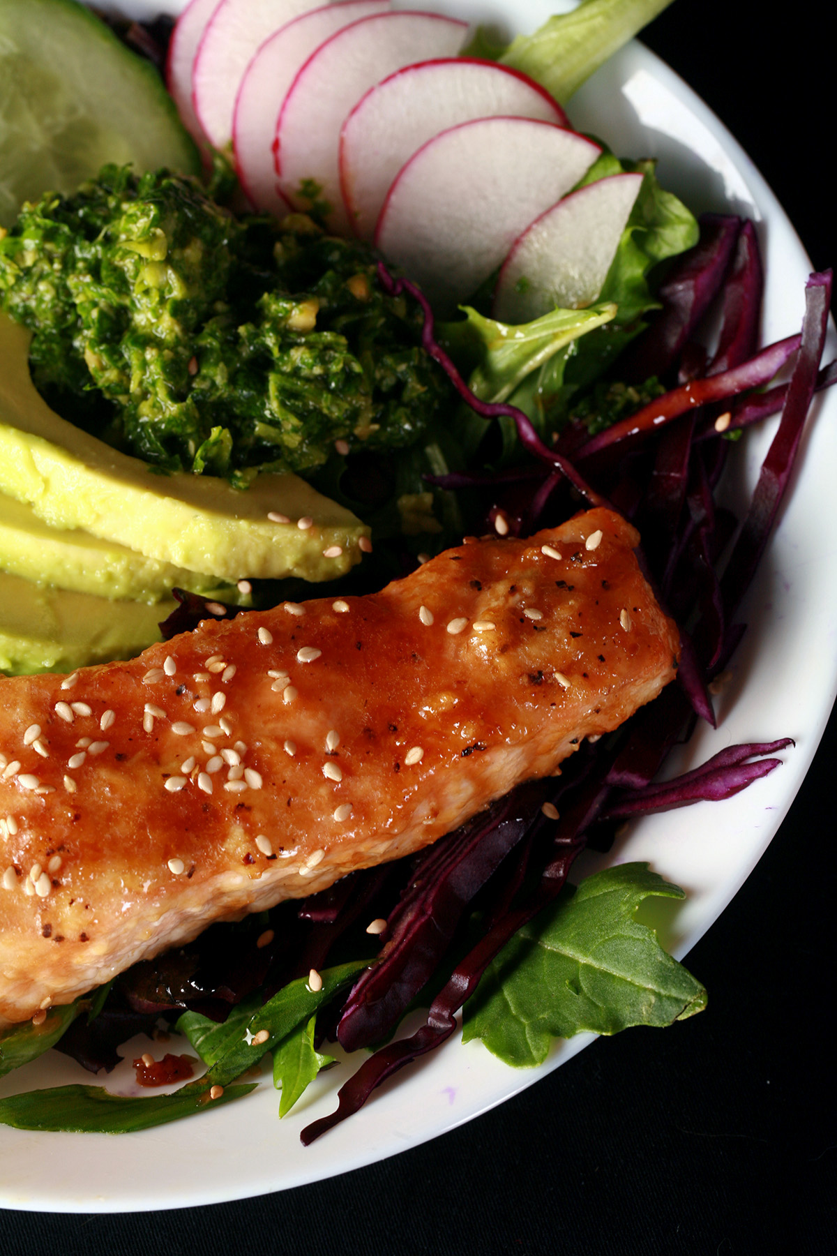 A portion of keto glazed sesame ginger salmon, in a bowl with veggies.