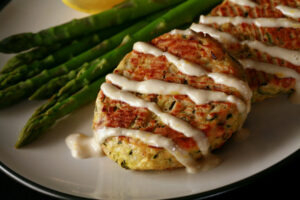 2 baked keto zucchini patties, drizzled with lemon tahini sauce.