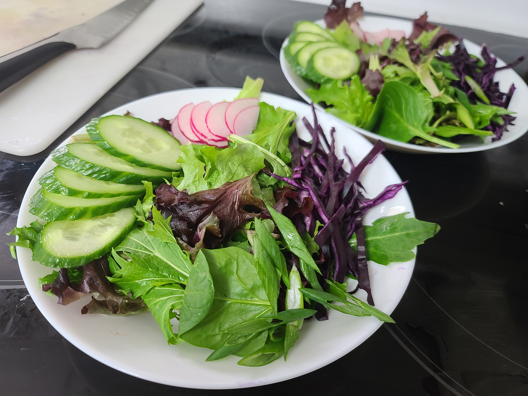 2 shallow bowls with colourful salads in each.