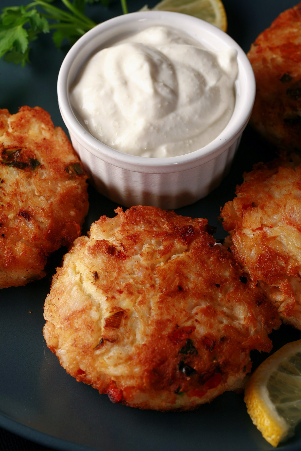 A plate of fried gluten free low carb crab cakes with a small bowl of horseradish sauce.