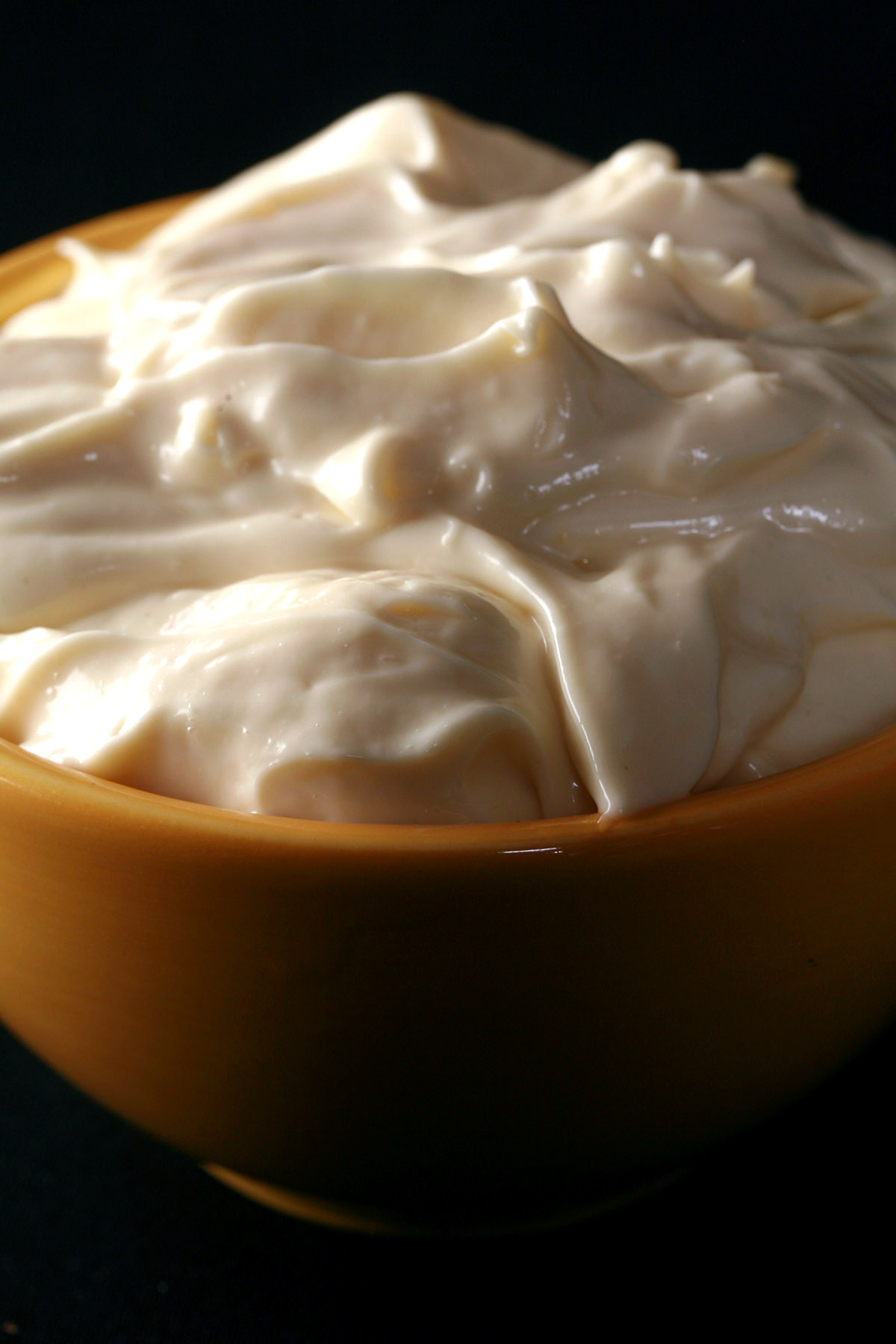 A close up photo of a yellow bowl full of keto mayonnaise.