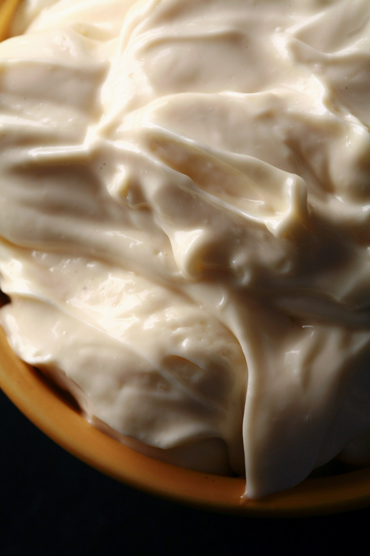 A close up photo of a yellow bowl full of keto mayo.