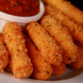 A plate of deep fried keto mozzarella sticks, with low carb marinara sauce.