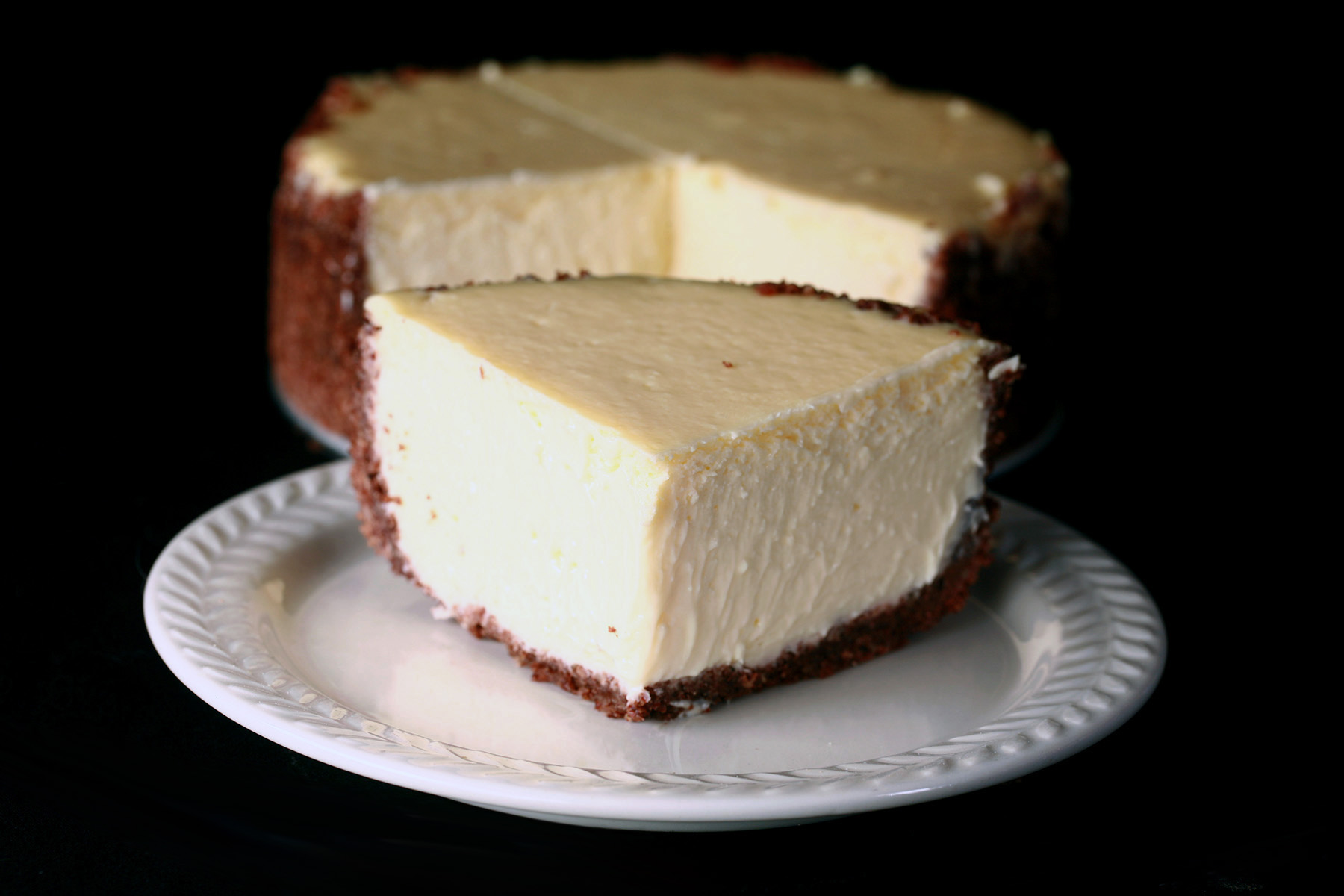 A small 6" vanilla keto cheesecake with a slice cut out of it.