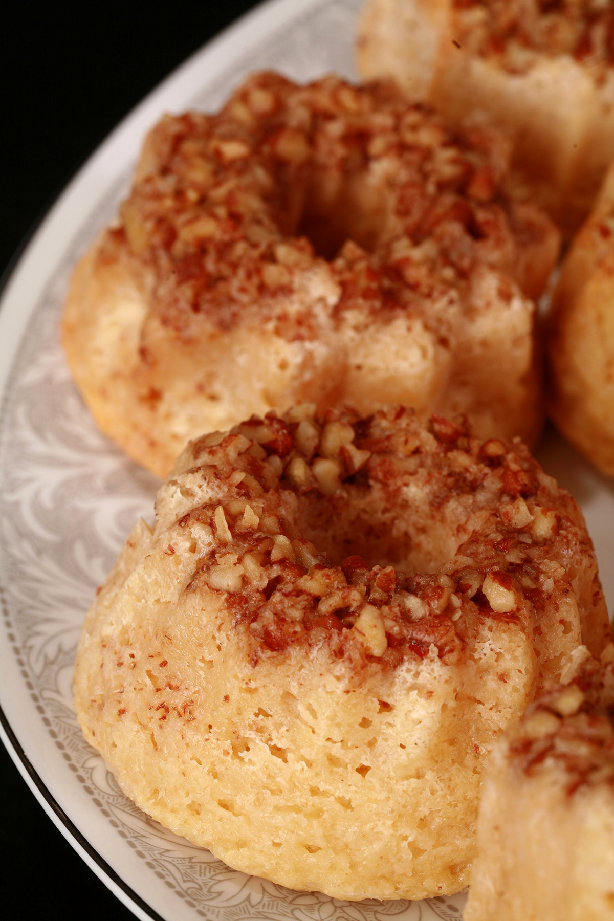 A plate of mini bundt keto rum cakes, each with pecan topping.