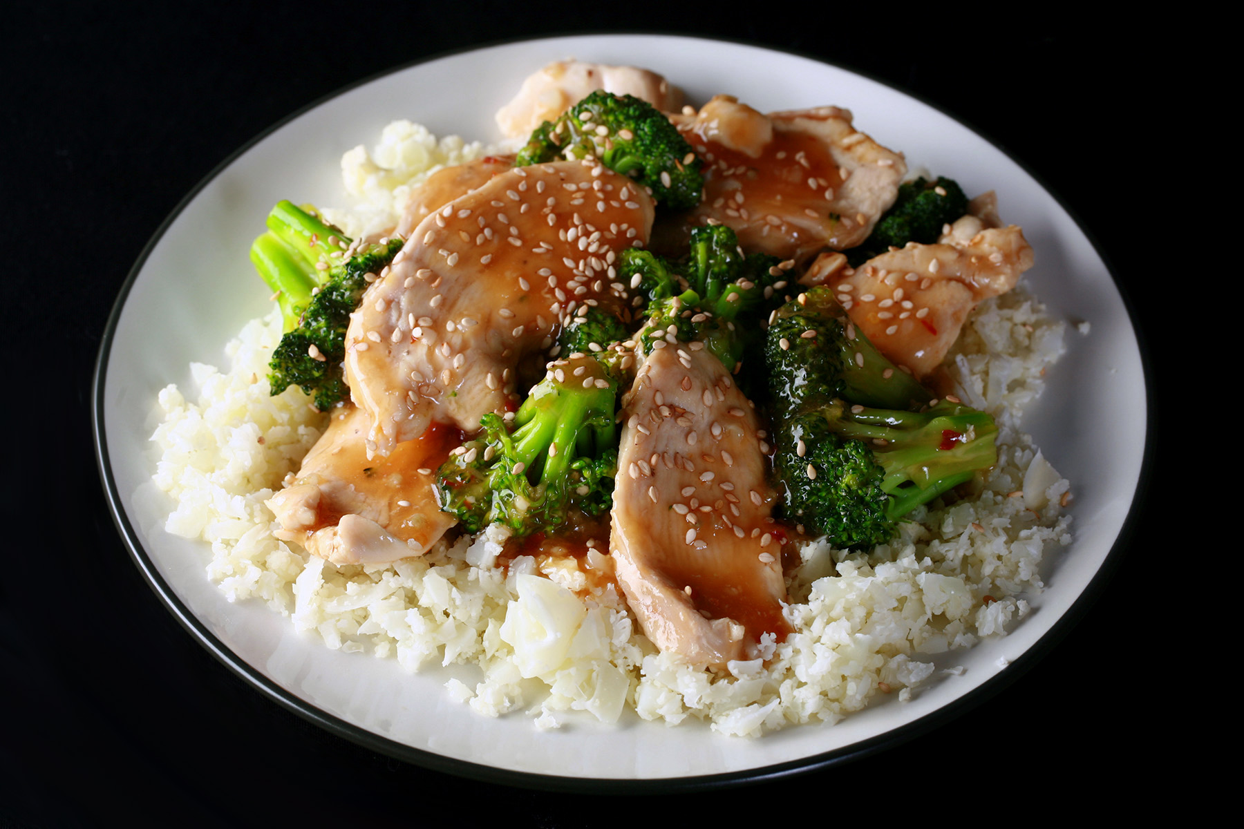 A plate of Keto Sesame Chicken, served on Cauliflower rice.