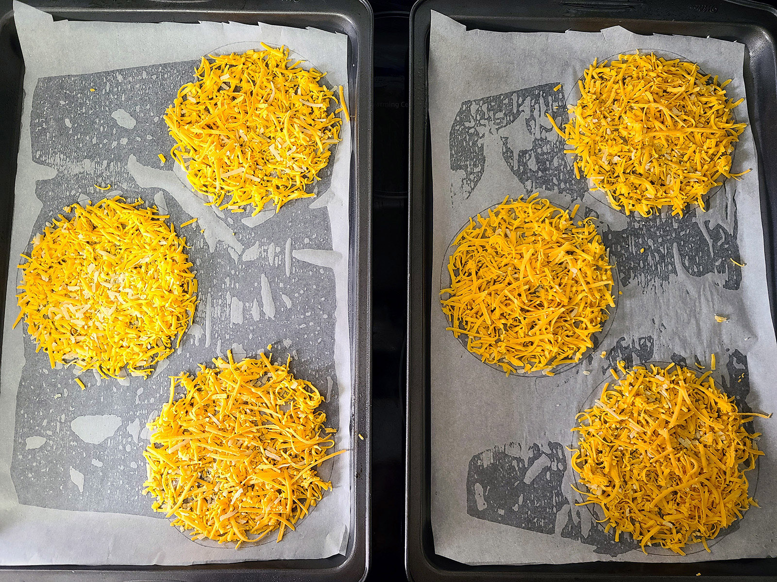 2 prepared pans, each with 3 rounds of cheese keto taco shells ready for the oven.