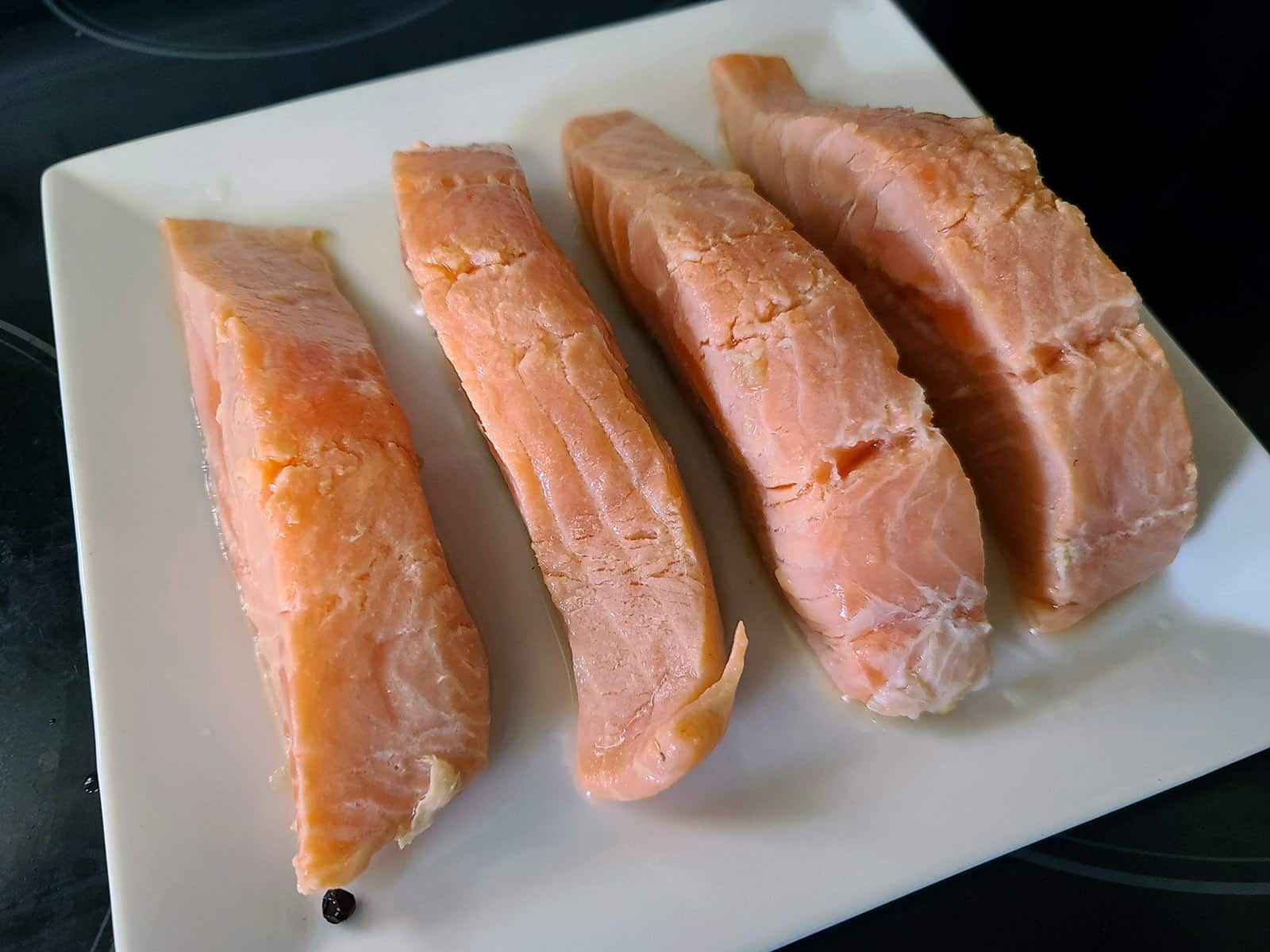 4 sections of brined salmon on a plate.
