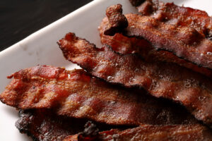 A plate piled high with crispy smoked bacon slices.