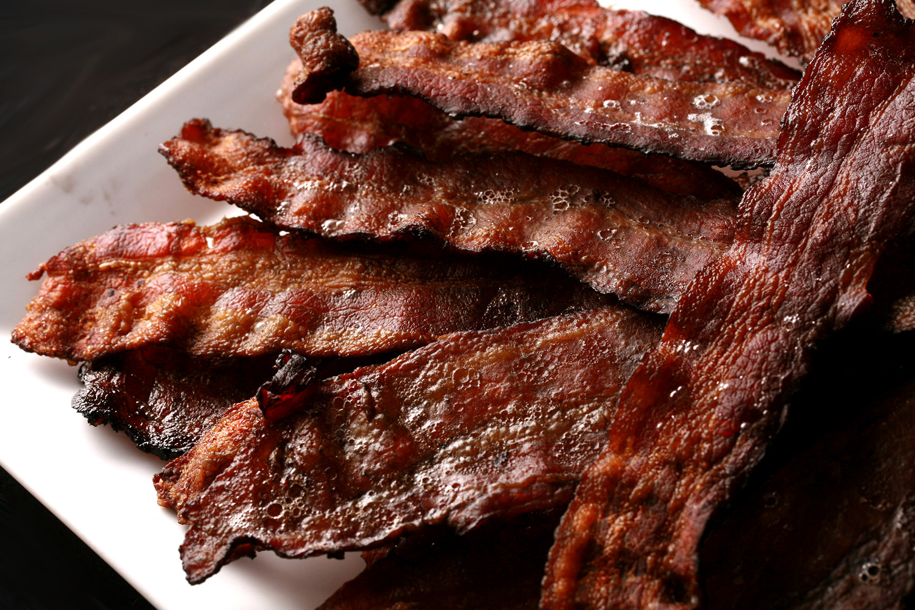 A plate piled high with crispy smoked bacon slices.