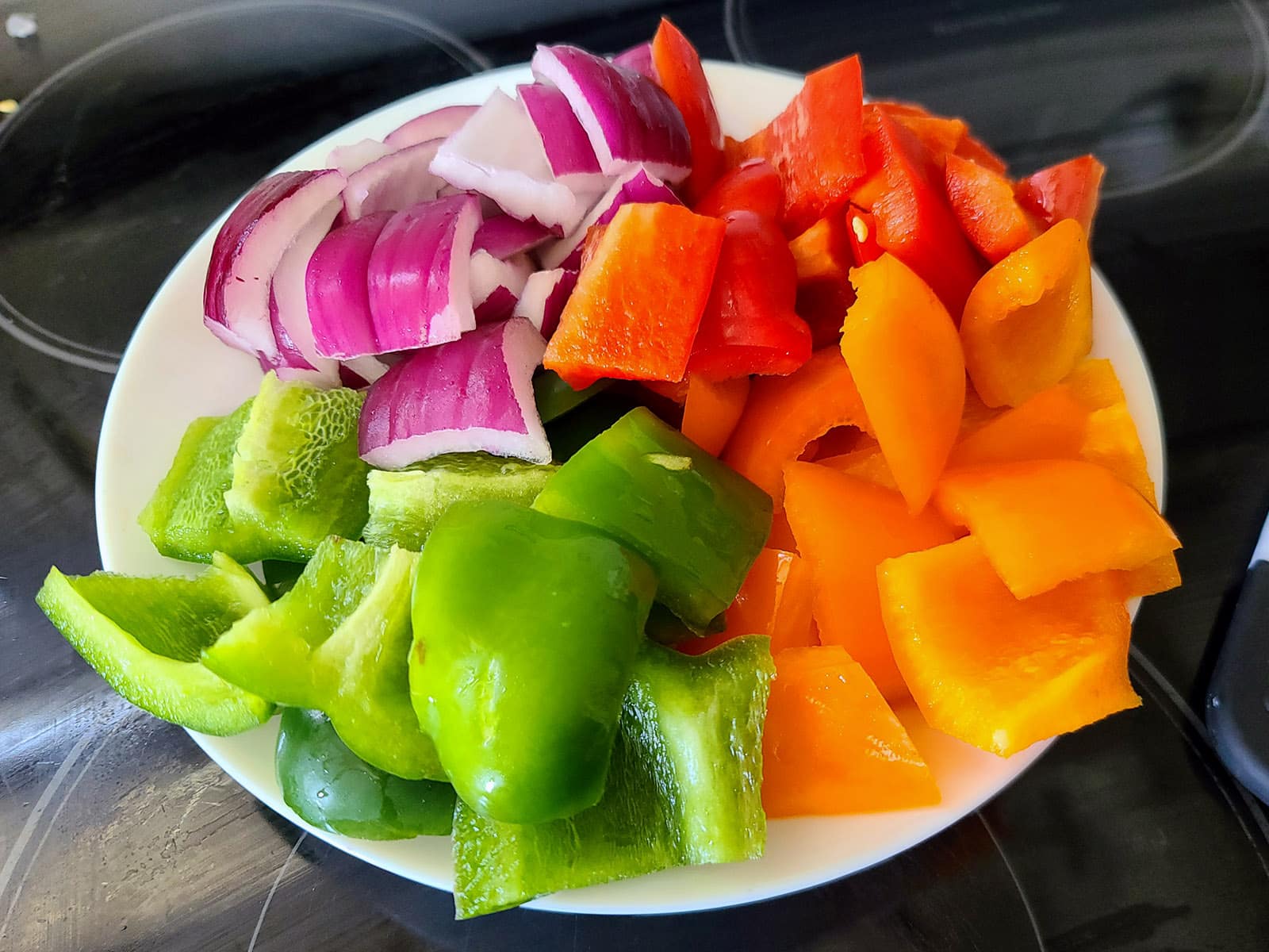A bowl of cut up bell peppers and red onion.