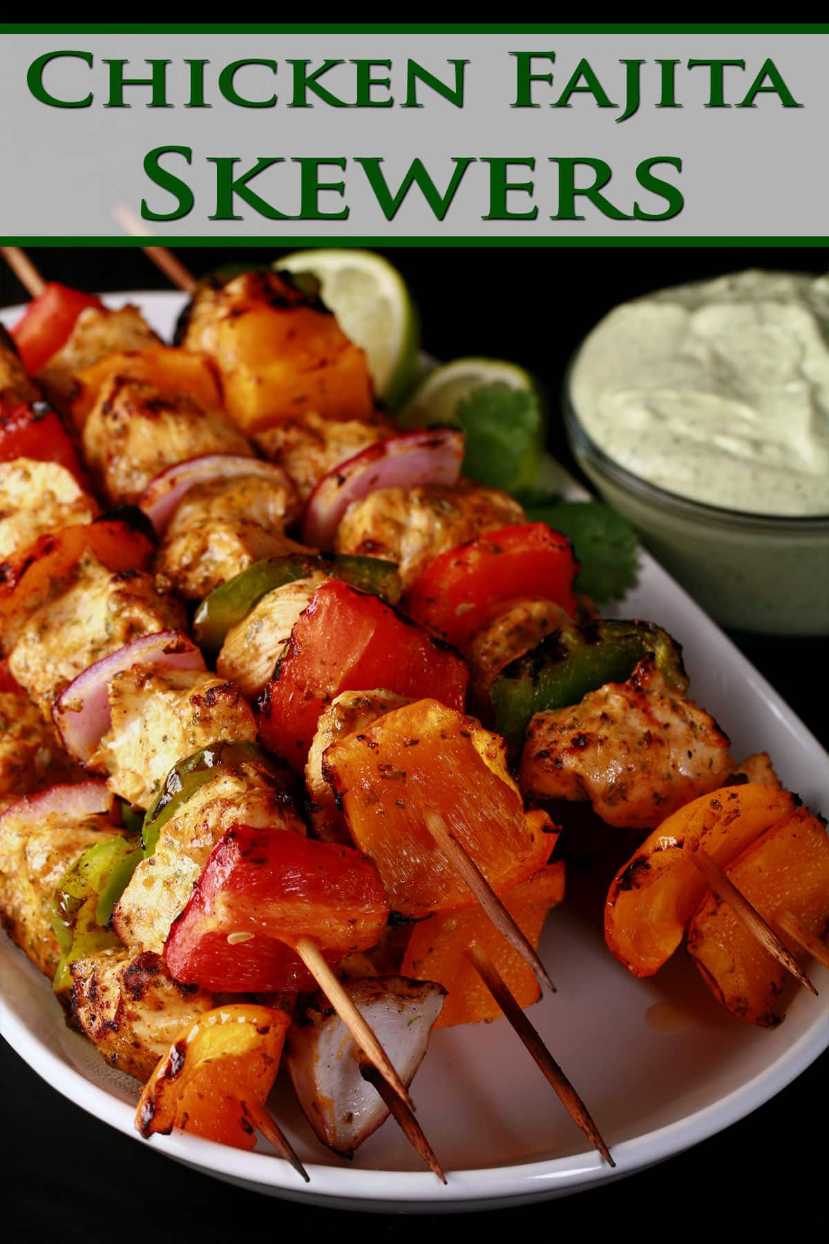 A tray of fajita chicken skewers with a bowl of avocado crema next to it.