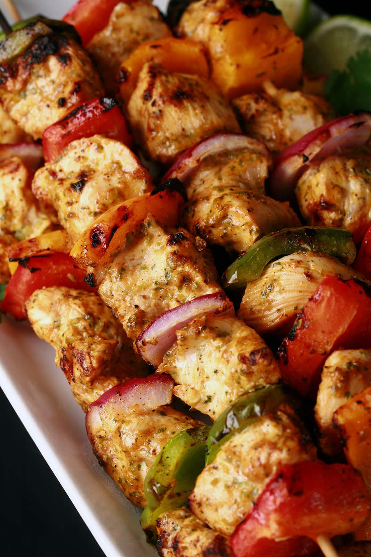 A tray of fajita chicken kebabs with a bowl of avocado crema next to it.