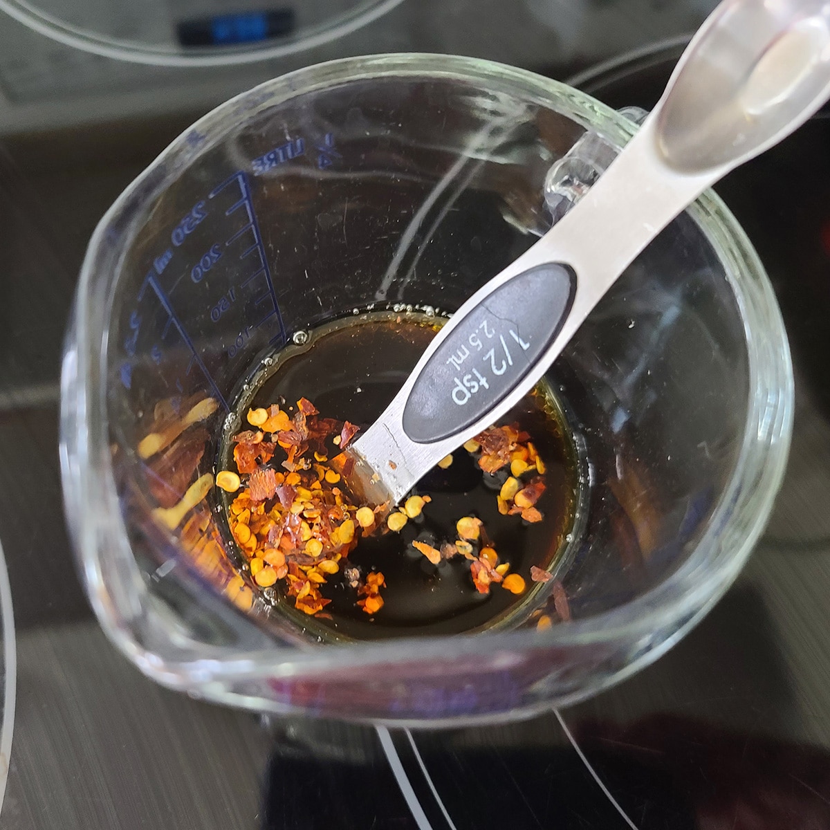 A glass measuring cup with sauce ingredients in it.