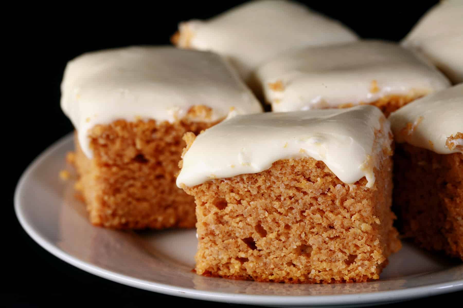 A plate of keto pumpkin cake bars with cream cheese frosting.