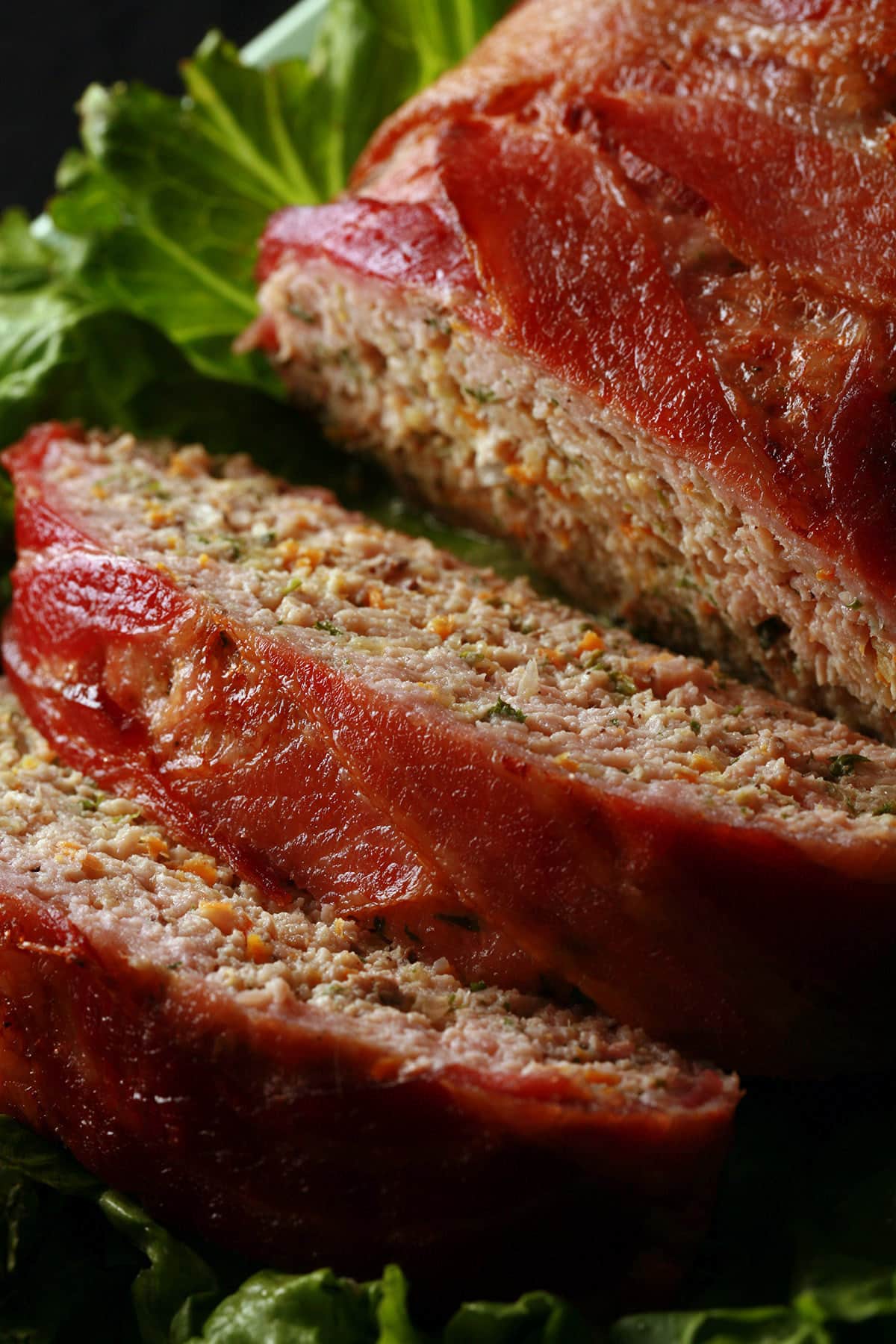 A close up view of a keto bacon wrapped meatloaf.  Shredded veggies are visible.