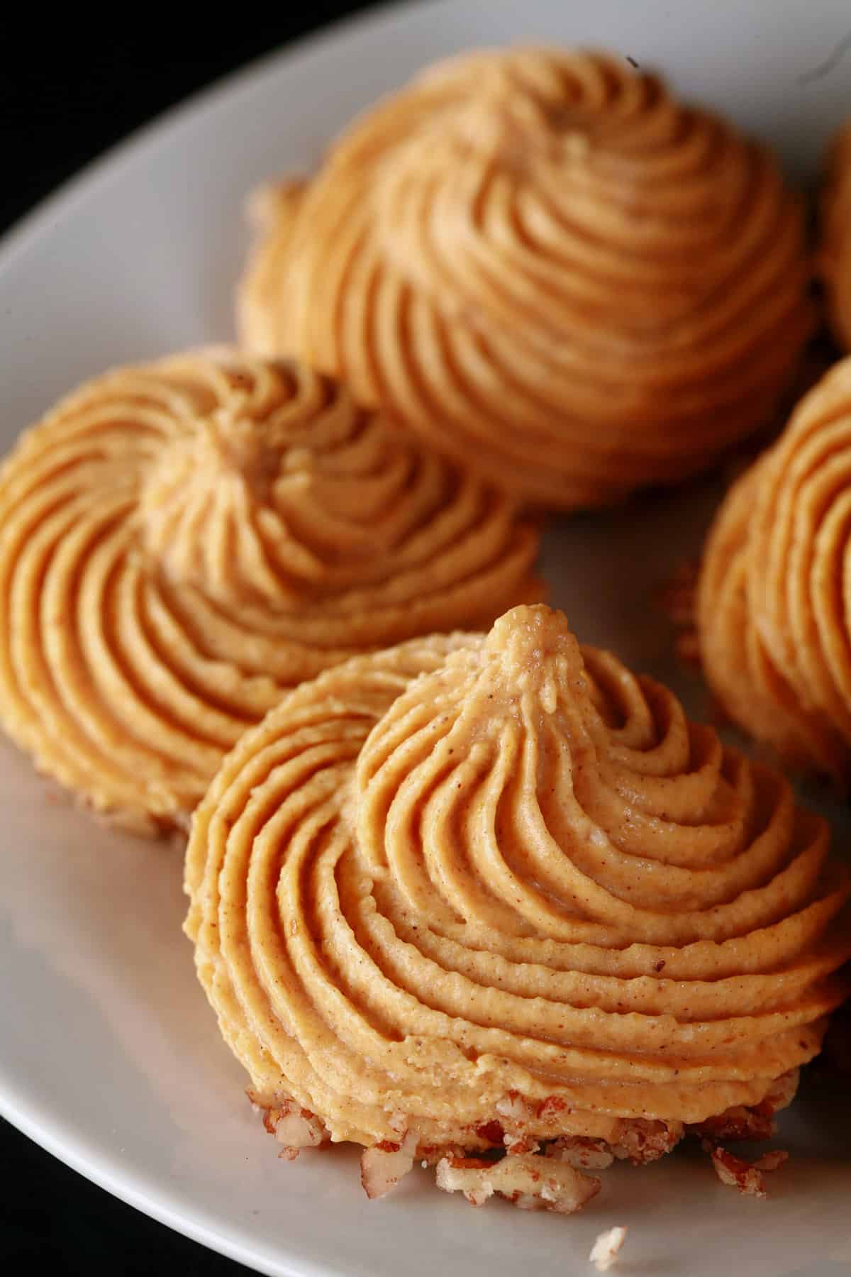 A plate of swirl piped keto pumpkin pie fat bombs.