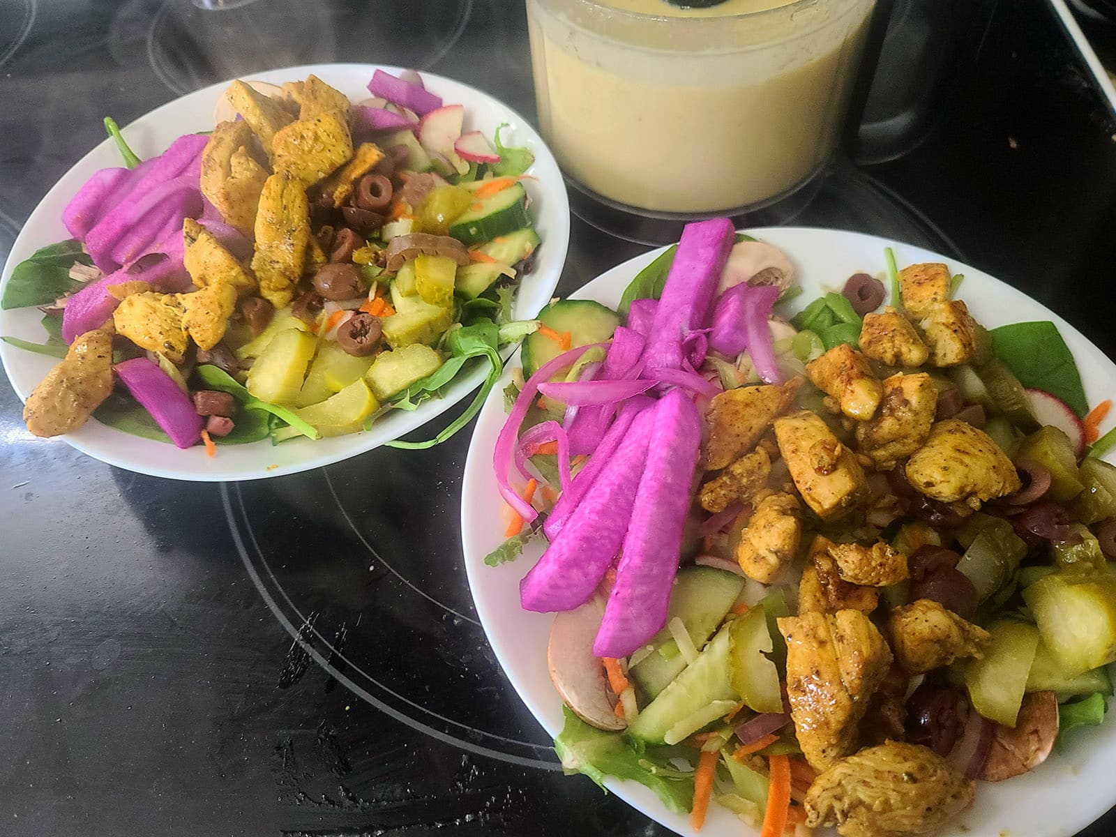 Two bowls of salad with shawarma chicken and bright pink pickled turnips.