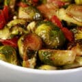 A large white bowl of keto bacon roasted brussels sprouts.