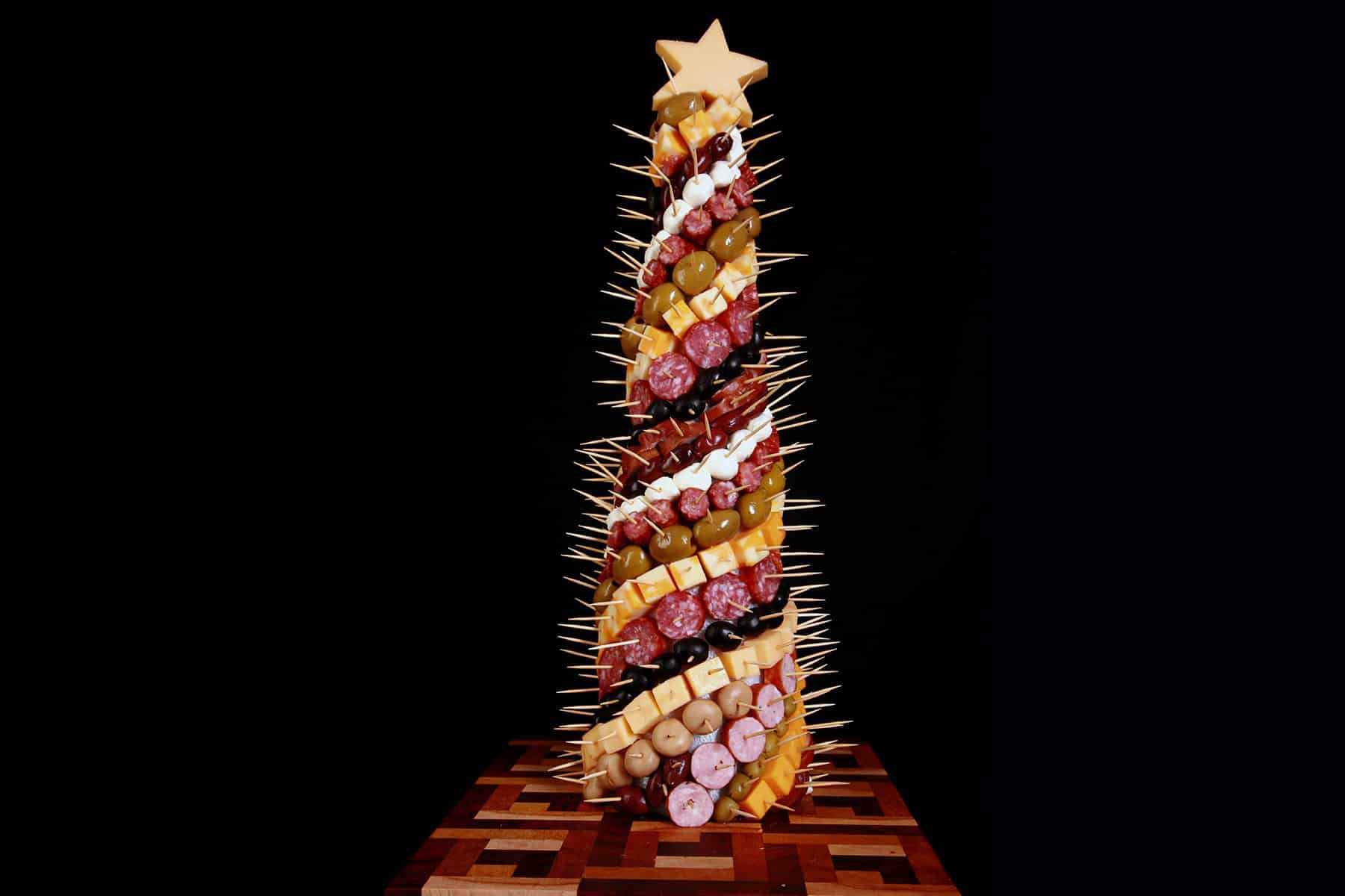 A charcuterie christmas tree, covered in cheese, olives, and cured meats.