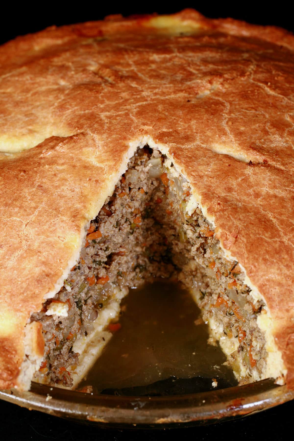 A close up view of a keto tourtiere with one slice removed from it.